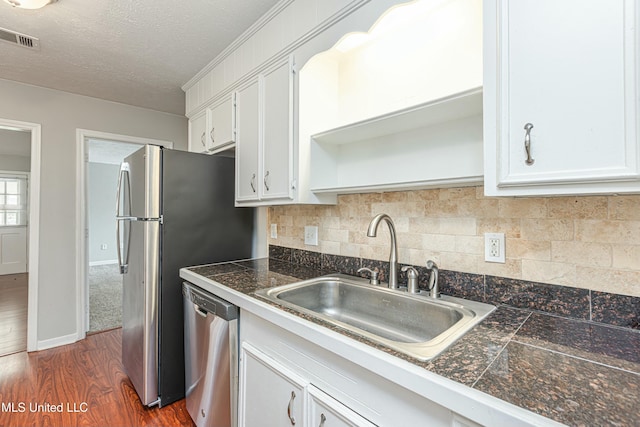 kitchen featuring sink, white cabinetry, appliances with stainless steel finishes, dark hardwood / wood-style flooring, and backsplash