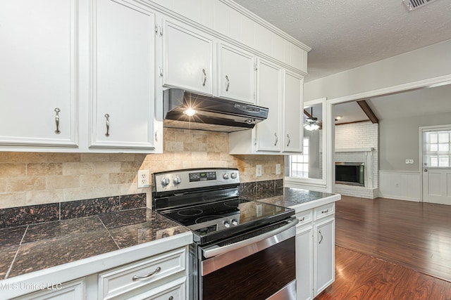 kitchen featuring white cabinetry, a brick fireplace, a textured ceiling, dark hardwood / wood-style floors, and electric stove