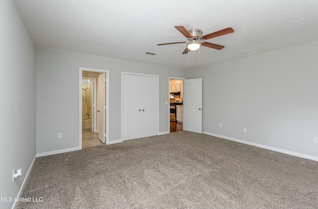 unfurnished bedroom with ensuite bath, ceiling fan, a textured ceiling, light colored carpet, and a closet