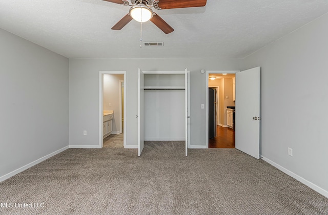 unfurnished bedroom featuring light carpet, ensuite bath, a closet, and a textured ceiling