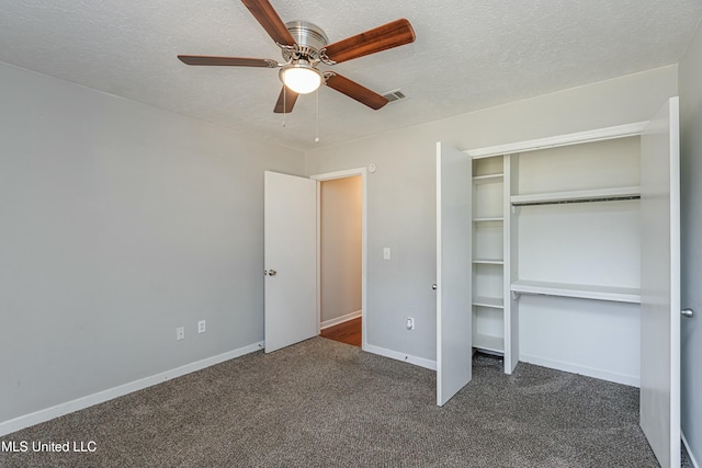 unfurnished bedroom featuring ceiling fan, dark carpet, a closet, and a textured ceiling