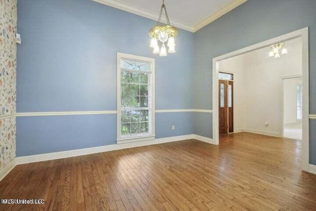 empty room with an inviting chandelier, ornamental molding, and wood-type flooring