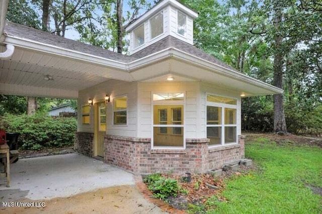 7828 Loa Pl, Diamondhead, MS 39525 - view of side of property featuring a lawn, brick siding, a patio, roof with shingles, and a carport