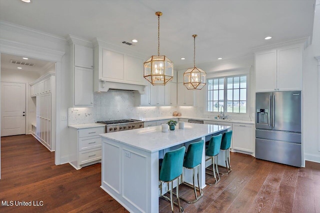 kitchen featuring dark wood-type flooring, stainless steel appliances, white cabinetry, and a kitchen island