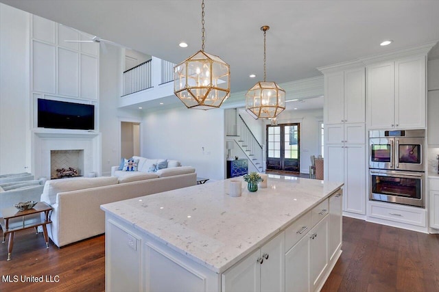 kitchen with dark hardwood / wood-style flooring, pendant lighting, a kitchen island, and white cabinets