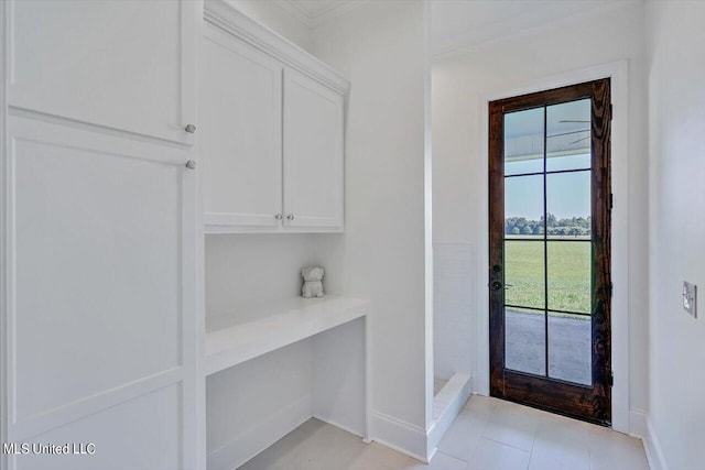 doorway with crown molding and light tile patterned floors