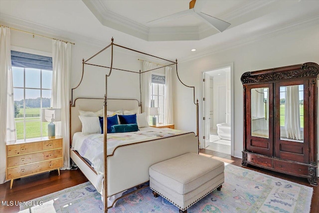 bedroom with hardwood / wood-style floors, ceiling fan, a tray ceiling, and ensuite bath