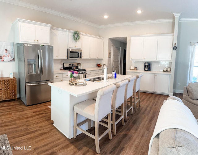 kitchen featuring dark wood-style flooring, backsplash, appliances with stainless steel finishes, white cabinets, and a sink