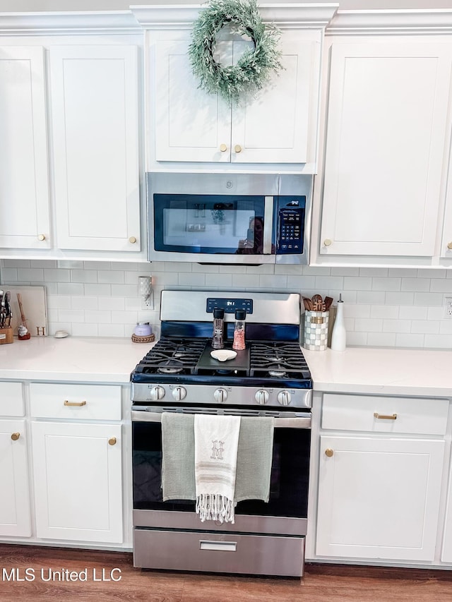 kitchen featuring stainless steel appliances, white cabinets, and backsplash