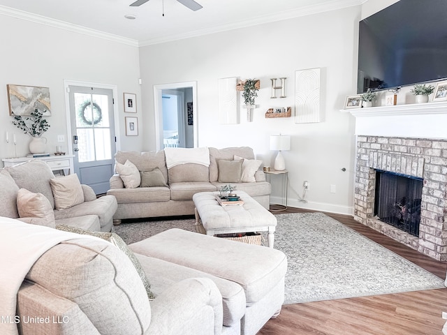 living area featuring a fireplace, crown molding, ceiling fan, wood finished floors, and baseboards