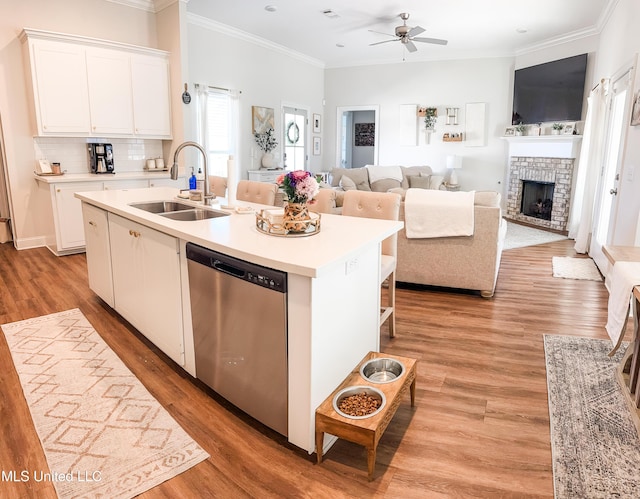 kitchen featuring a center island with sink, light countertops, a sink, and stainless steel dishwasher