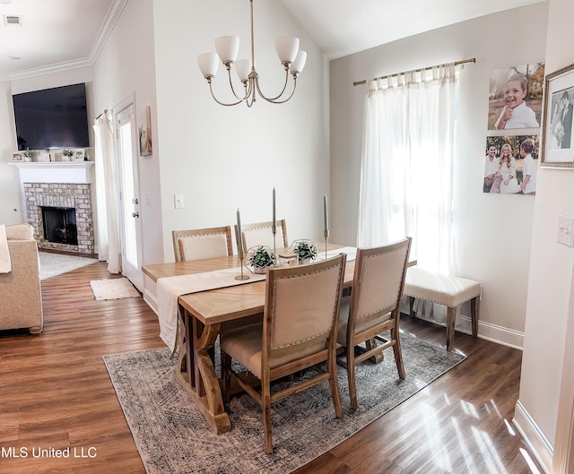 dining room with a notable chandelier, a fireplace, baseboards, and wood finished floors