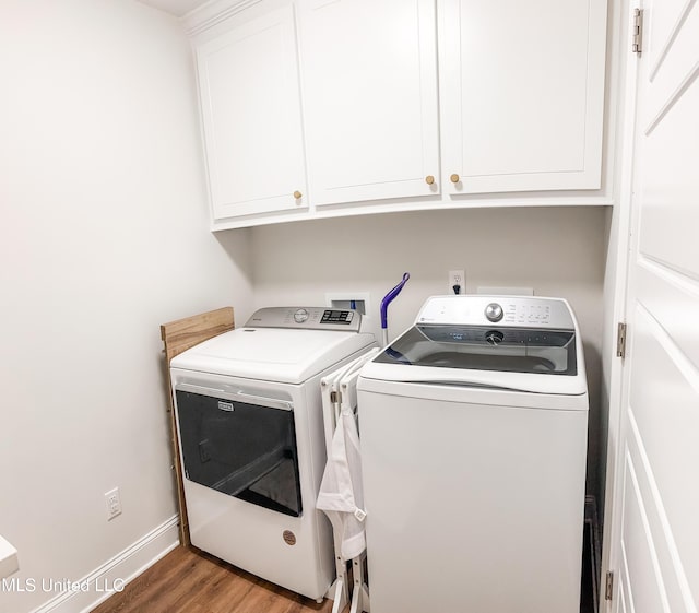 laundry area featuring baseboards, cabinet space, washing machine and clothes dryer, and wood finished floors