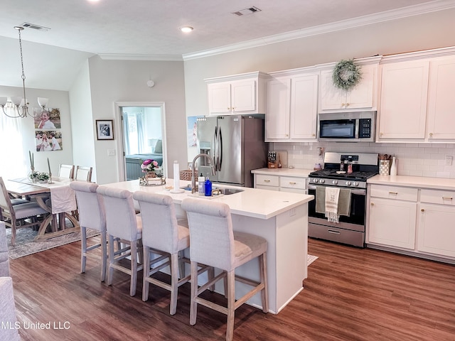 kitchen with appliances with stainless steel finishes, visible vents, a sink, and a kitchen breakfast bar