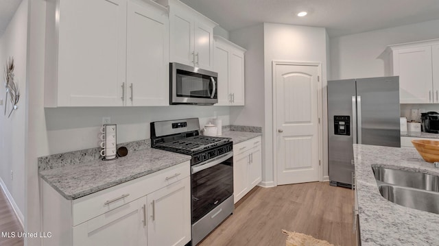 96 Twin Lakes Dr, Byhalia, MS 38611 - kitchen with stainless steel appliances, light wood-style flooring, white cabinets, recessed lighting, and light stone countertops