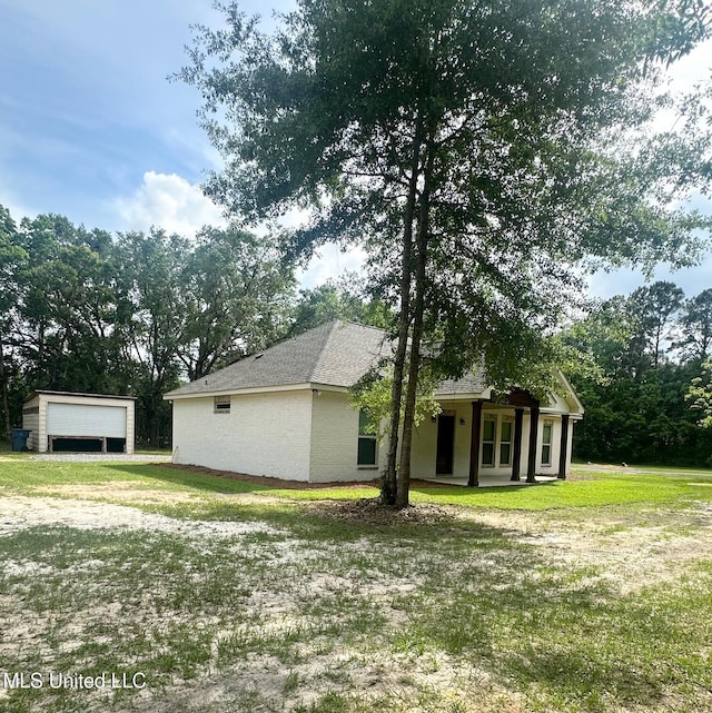 exterior space featuring a yard, a detached garage, and covered porch