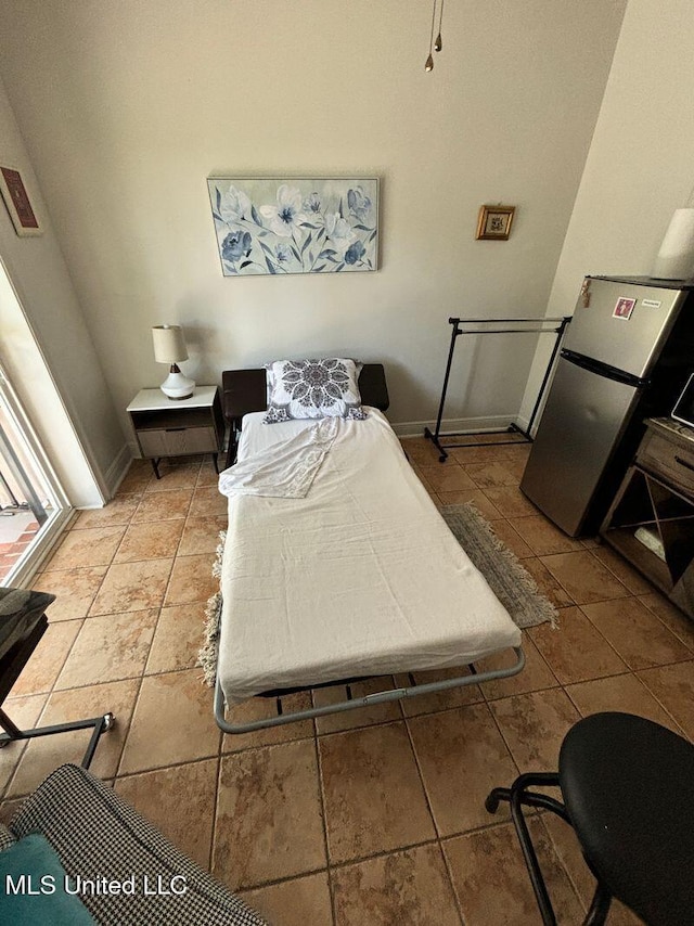 tiled bedroom featuring baseboards and freestanding refrigerator