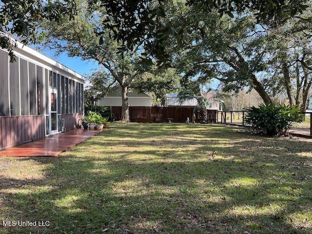 view of yard featuring a sunroom and fence