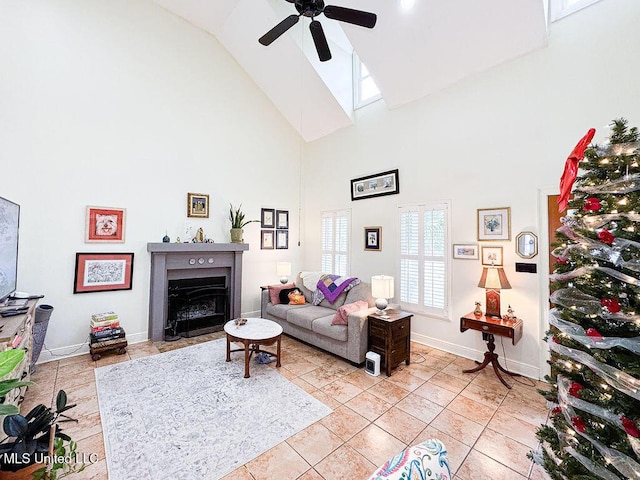 living area with baseboards, a ceiling fan, a fireplace with flush hearth, high vaulted ceiling, and light tile patterned flooring