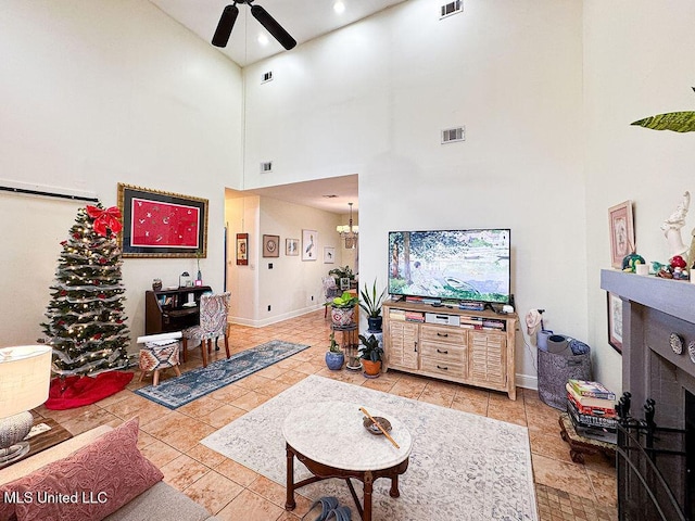 tiled living room featuring ceiling fan with notable chandelier, visible vents, and baseboards