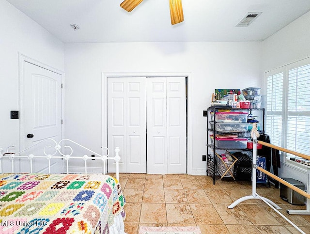 bedroom featuring a closet, visible vents, light tile patterned flooring, ceiling fan, and baseboards