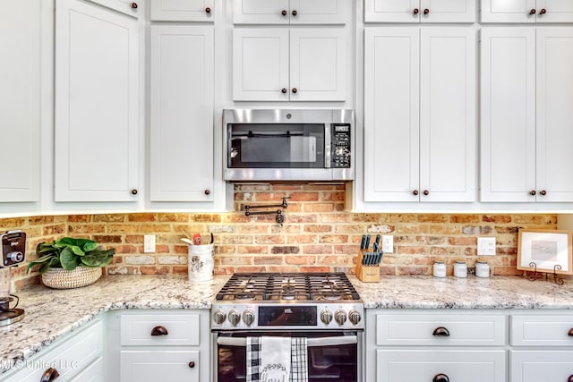 150 Pine Ridge Cir, Brandon, MS 39047 - kitchen featuring backsplash, light stone counters, white cabinetry, and stainless steel appliances