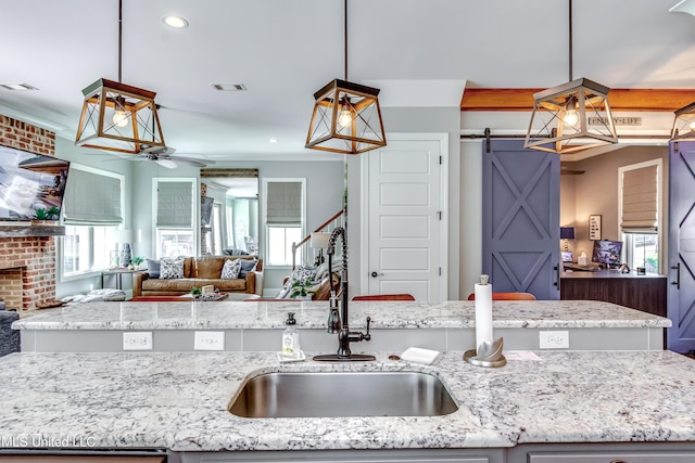 150 Pine Ridge Cir, Brandon, MS 39047 - kitchen with light stone counters, a barn door, ceiling fan, a sink, and open floor plan