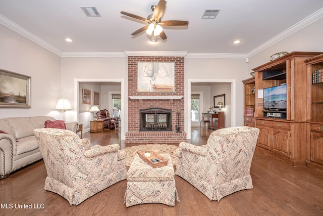 living room with wood-type flooring, ornamental molding, and a brick fireplace