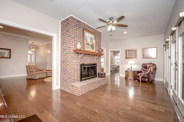 unfurnished living room featuring ornamental molding, wood-type flooring, ceiling fan, and a fireplace