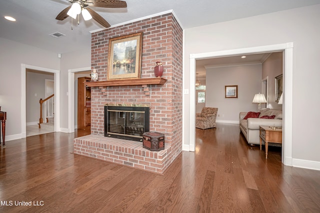 living room featuring a fireplace, dark hardwood / wood-style flooring, ceiling fan, and crown molding