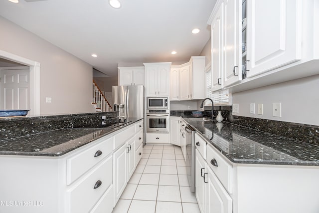 kitchen featuring dark stone counters, white cabinetry, light tile patterned floors, and appliances with stainless steel finishes