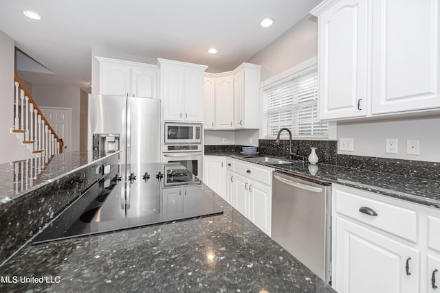 kitchen with white cabinets, appliances with stainless steel finishes, sink, and dark stone countertops