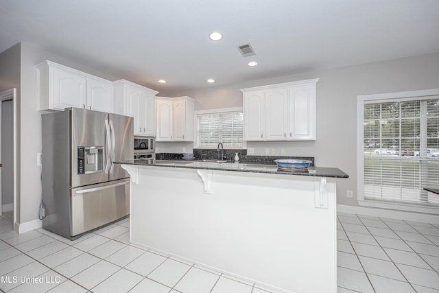 kitchen featuring white cabinets, light tile patterned floors, a kitchen island, and appliances with stainless steel finishes