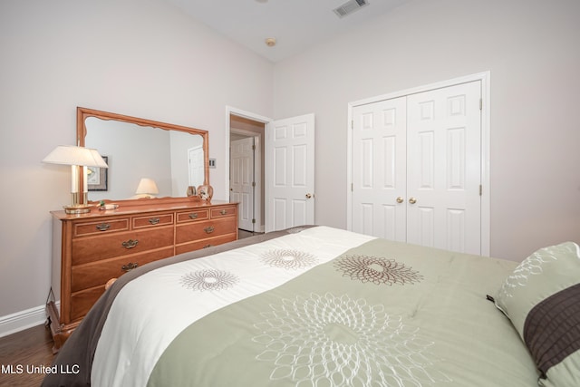 bedroom with dark hardwood / wood-style floors and a closet