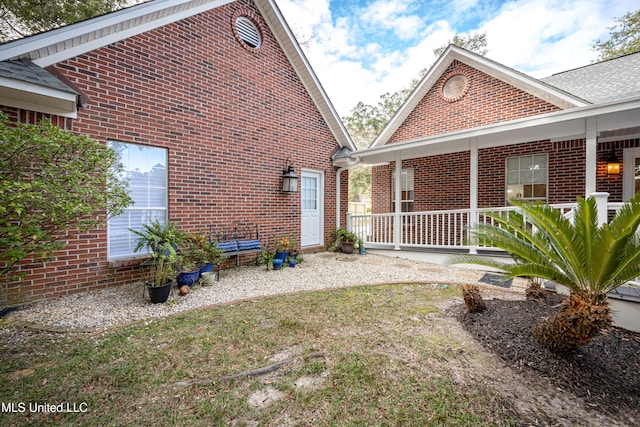 back of property with a lawn and a porch