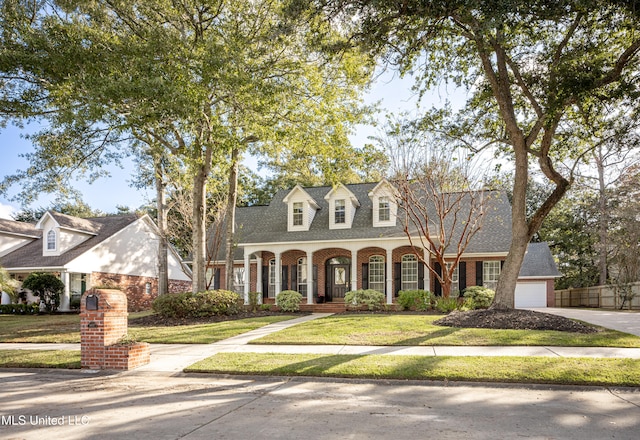 cape cod house with a front lawn, a garage, and covered porch