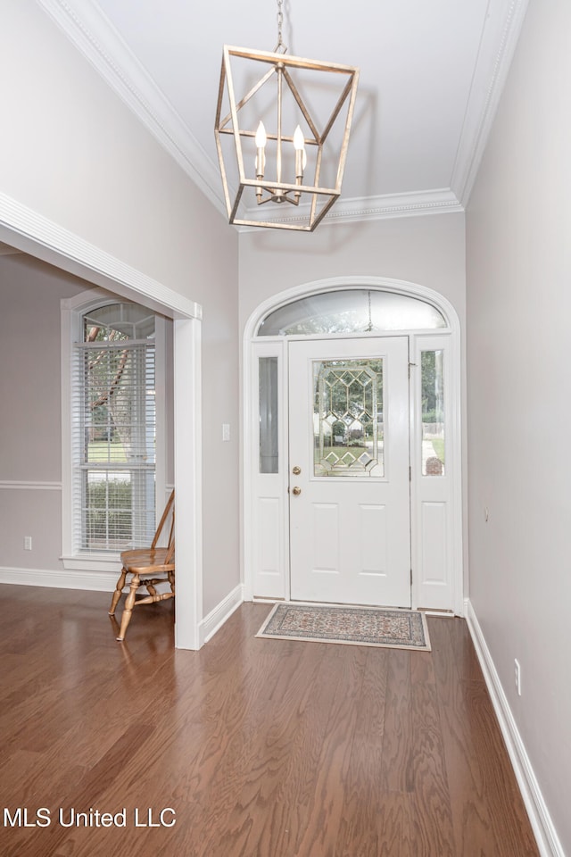 entrance foyer featuring dark wood-type flooring, crown molding, and a notable chandelier