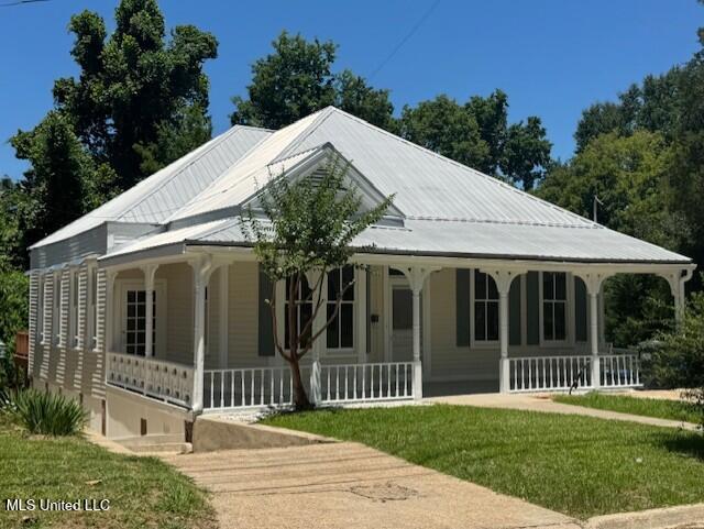 farmhouse with covered porch and a front lawn