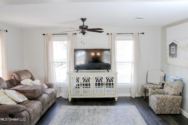 living room featuring dark wood-type flooring, ceiling fan, and plenty of natural light