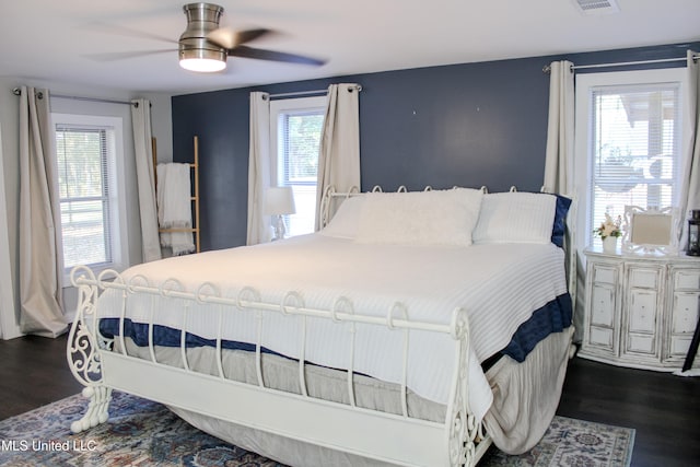 bedroom featuring dark wood-type flooring, multiple windows, and ceiling fan