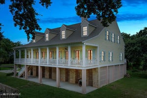 back house at dusk featuring a patio area and a lawn