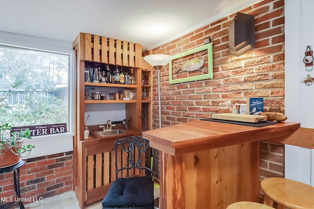 bar with brick wall, sink, and butcher block countertops