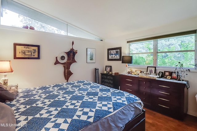 bedroom with multiple windows, vaulted ceiling, and dark colored carpet