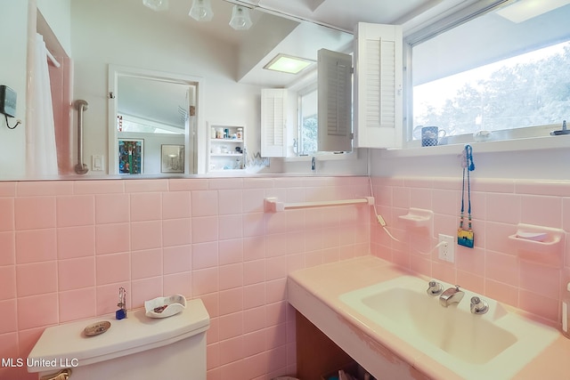 bathroom featuring sink, tile walls, and toilet