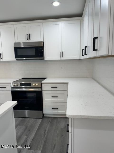 kitchen with dark wood-type flooring, appliances with stainless steel finishes, and white cabinets