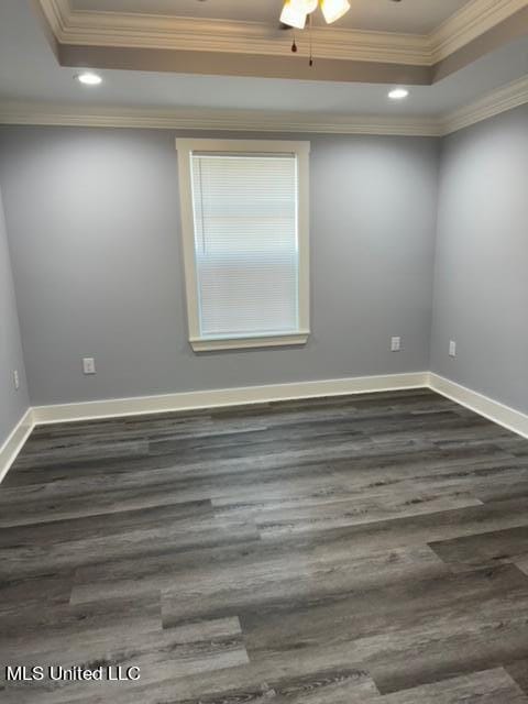 empty room featuring crown molding, a raised ceiling, dark hardwood / wood-style flooring, and ceiling fan