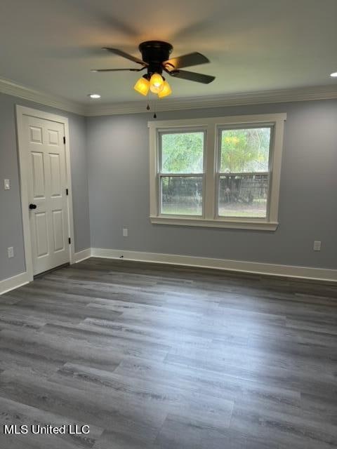 spare room featuring dark wood-type flooring, ceiling fan, and ornamental molding