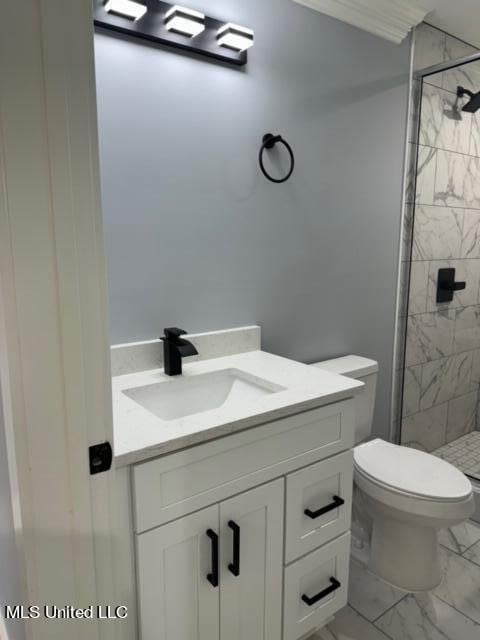 bathroom featuring toilet, vanity, and tiled shower