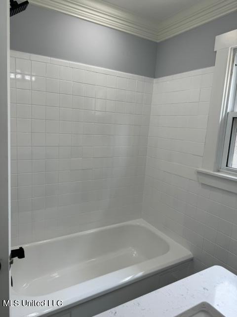 bathroom with crown molding and tiled shower / bath combo