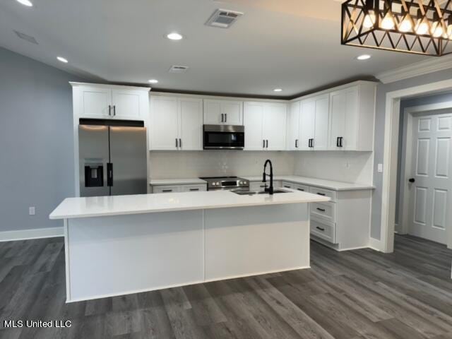 kitchen with white cabinetry, stainless steel appliances, pendant lighting, and an island with sink